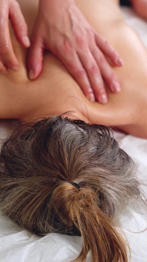 Closeup of back massage on blonde woman during relaxing spa therapy session