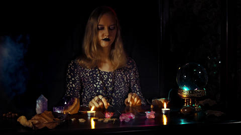 Woman psychic lays out tarot cards during a divination ritual with crystal ball
