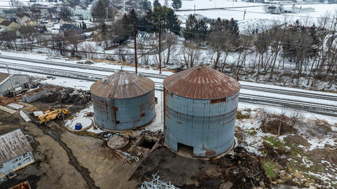 Two Large Silos Stand Near Railroad Tracks in a Rural Area During Winter Months