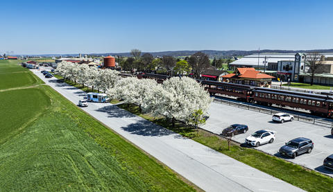 Train Station Area With Blooming Trees and Parked Cars in a Rural Setting on a