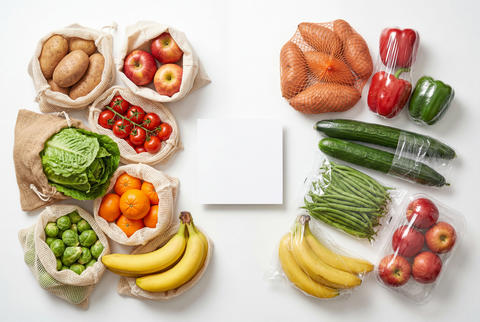 Fresh produce in reusable mesh bags and plastic packaging around a blank square