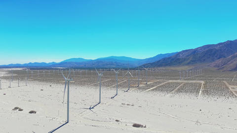 Aerial drone view of desert windmills in Palm Springs California surrounded by mountains and dry