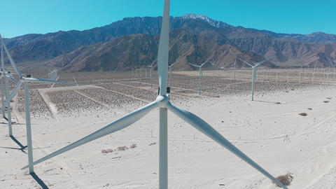 Aerial cinematic view of single windmill turbine in Palm Springs desert surrounded by mountains and