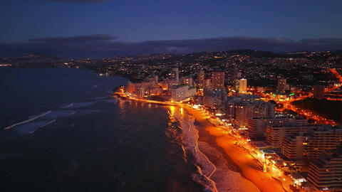 Aerial Shot Of City During Blue Hour Showcasing Glowing Streets And Lively Shoreline Atmosphere