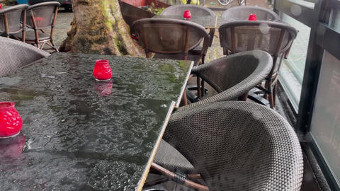 Empty cafe open terrace under rain, water droplets fall on wet tables and chairs