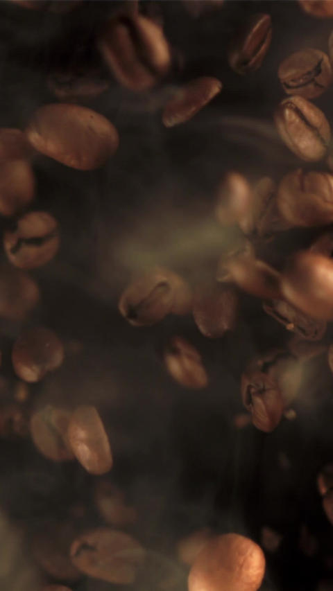 Super slow motion of coffee beans with hot steam on a black background