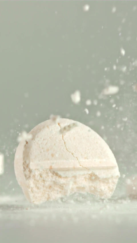 The pill falls on the table and splits into pieces. Filmed on a high-speed