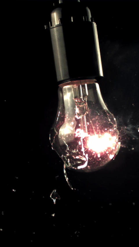 Super slow motion light bulb breaks into rattles. On a black background