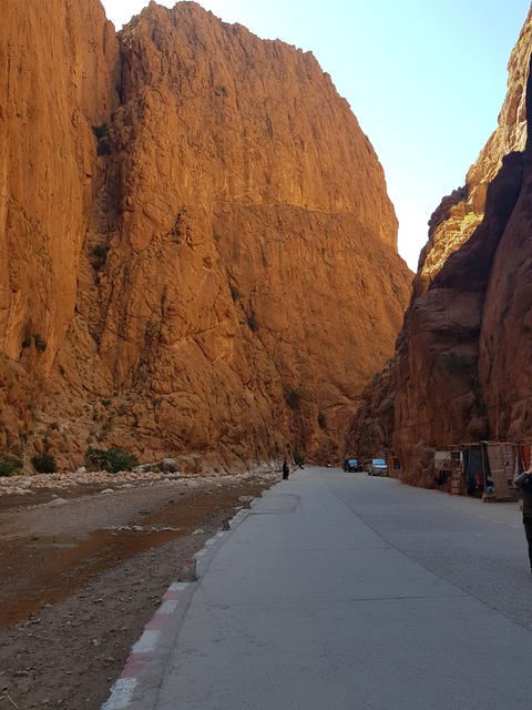 A person stands in front of a significant large rock formation