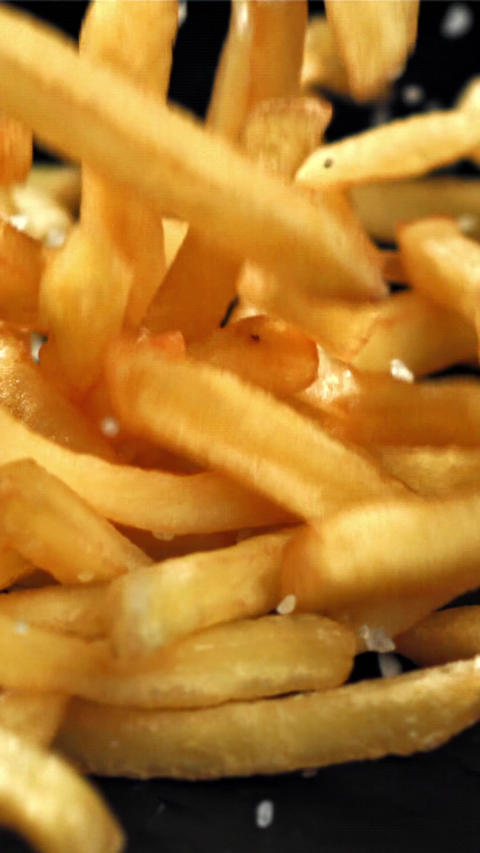 French fries with salt fall on the table. Filmed on a high-speed camera at 1000