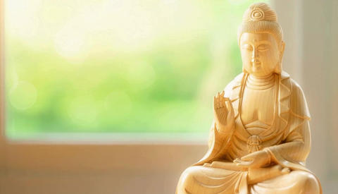 Wooden carving of Fugen Bodhisattva against a backdrop of fresh greenery