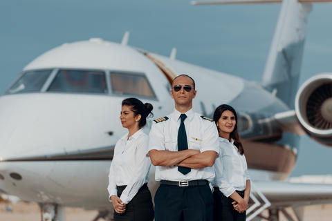 Pilot and flight crew standing confidently in front of a private jet ready for