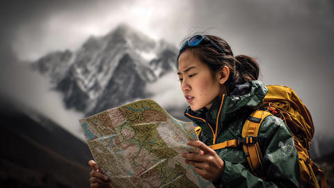 Female hiker reading paper map in snowy mountains, outdoor adventure travel