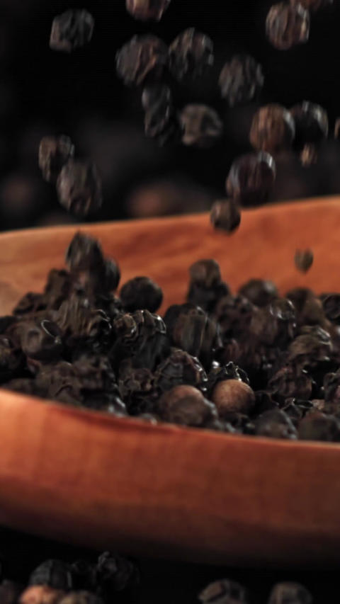 Black pepper falls on a wooden spoon. Filmed on a high-speed camera at 1000 fps