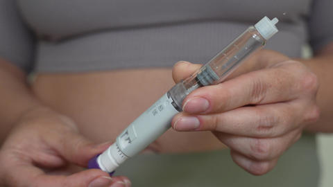 Woman setting dosage clicks on GLP-1 injection pen close-up