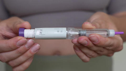 Woman setting dosage clicks on GLP-1 injection pen close-up