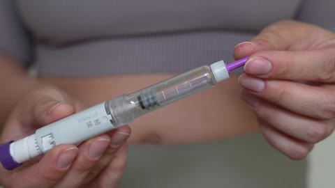 Woman holding GLP-1 injection pen for weight loss treatment close-up