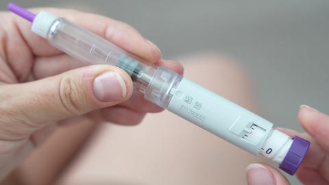 Woman setting dosage clicks on GLP-1 injection pen close-up