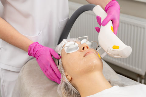 Professional woman receiving laser facial treatment
