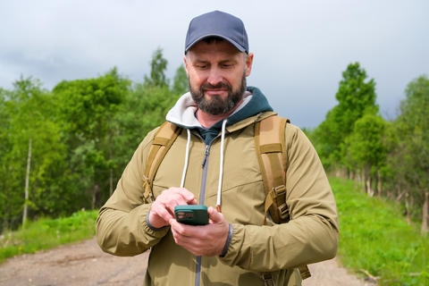 Using smartphone navigation, mature male tourist checks route information before continuing