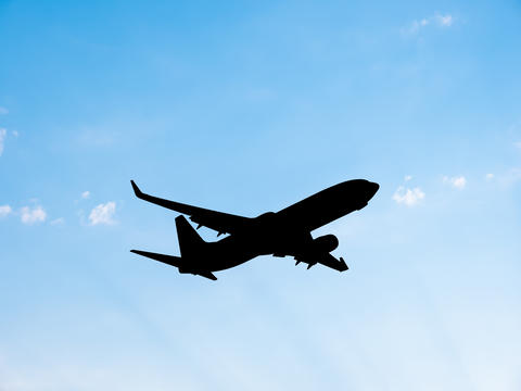 Airplane silhouette flying on blue sky