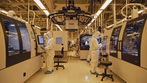 Semiconductor engineers supervise automated wafer processing equipment in a sterile cleanroom
