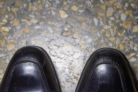 Top view of black leather formal shoes on terrazzo stone floor background