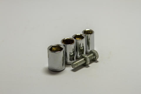 Set of chrome socket wrench heads with a steel bolt and nut on a white background
