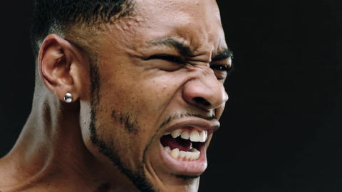 Young Black man shouting and expressing intense emotion close up shot against black background
