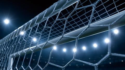 Soccer goal netting under bright stadium lights at night