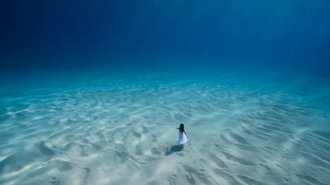 Woman dancing on ocean floor in underwater fantasy scene