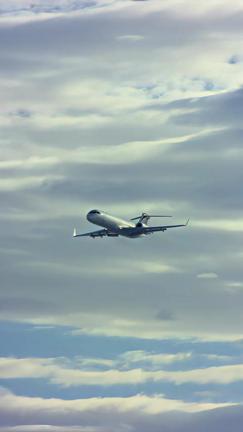 Business jet cruising above layered clouds in wide aerial view, capturing private aviation