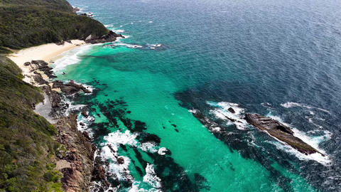Aerial video flying along the rugged rocky coastline towards McBrides Beach near Forster