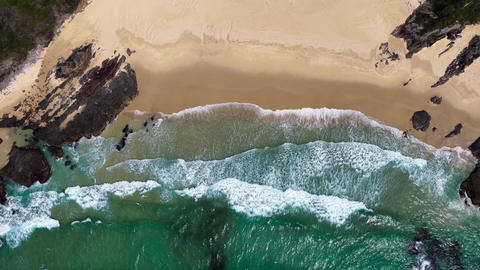 Aerial downward video capturing waves washing onto McBrides Beach near Forster