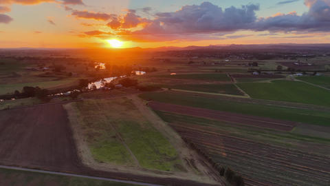 Aerial video flying over green and cultivated fields in Morpeth, NSW, Australia, towards sunset