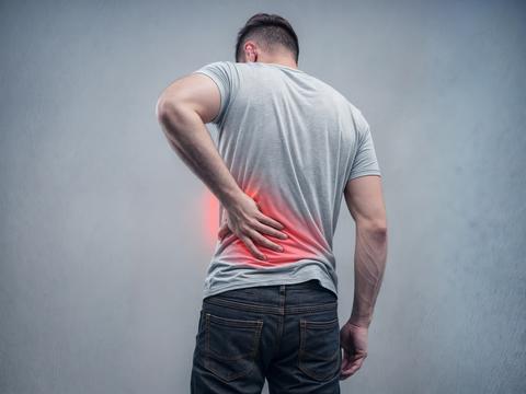 Man suffering from back pain, holding his lower back with his hand