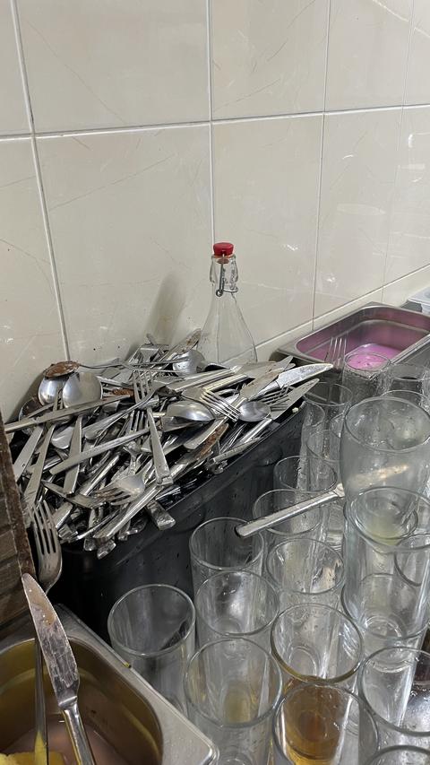 Dirty dishes and cutlery pile in restaurant kitchen sink photo, used forks, knives, spoons and