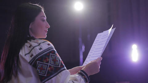 Ukrainian woman in vyshyvanka singing from sheet music