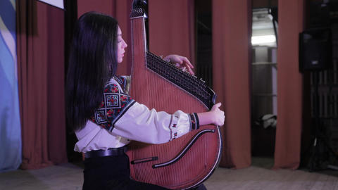 Ukrainian woman in traditional vyshyvanka playing the bandura