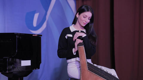 Young woman playing traditional ukrainian bandura instrument on stage