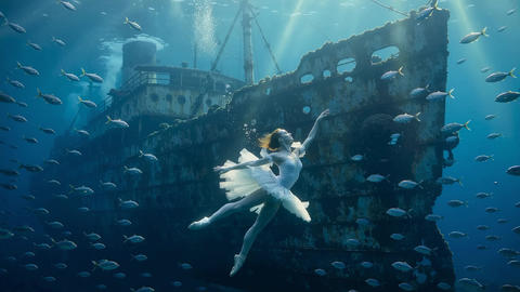 Underwater ballerina dancing near shipwreck in the ocean