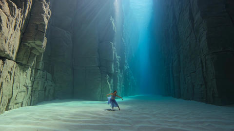 Person standing beneath dramatic light beam in canyon cavern