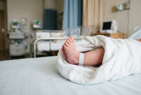 Close up of newborn baby feet with hospital identification band