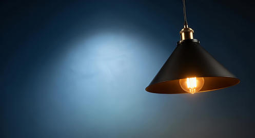 A black pendant light sways elegantly against a modern blue wall