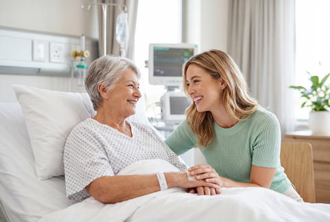 Loving daughter visiting senior mother in hospital bed