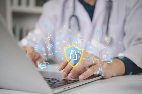 Doctor using laptop with cloud security shield hologram. Medical data protection, electronic health 