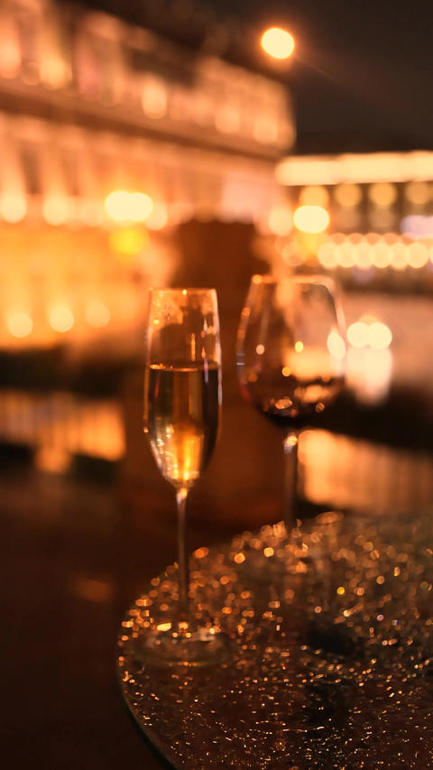 Wine and champagne glasses on terrace with warm city lights at evening