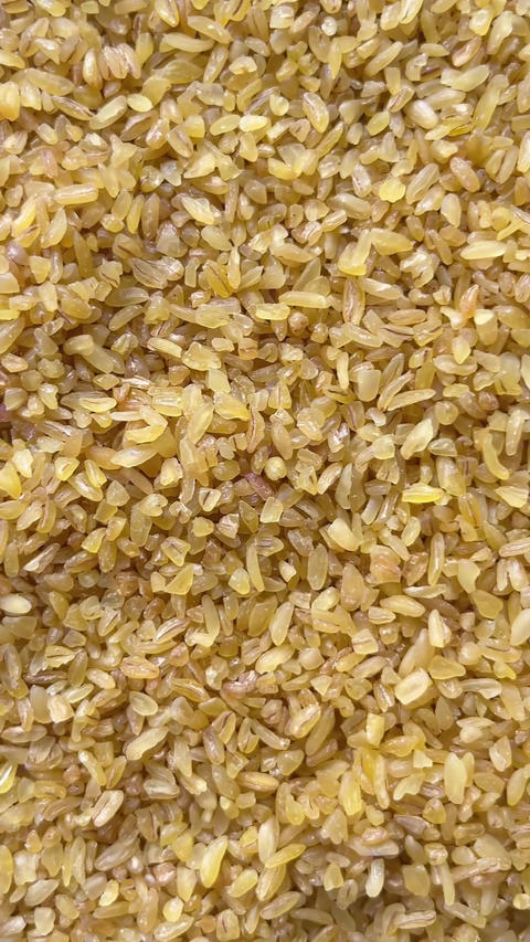 Vertical camera flyover above raw bulgur wheat groats macro texture