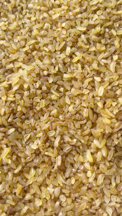 Vertical camera flyover above raw bulgur wheat groats macro texture