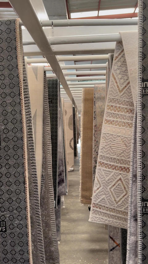 Patterned rugs hanging in a narrow warehouse aisle